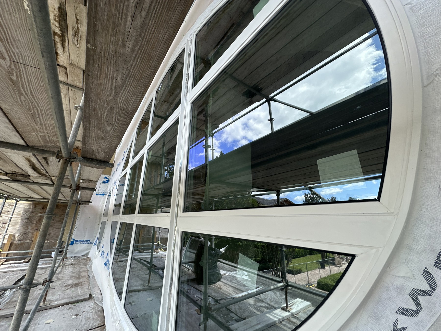 Custom curved architectural glass window under installation on a large home