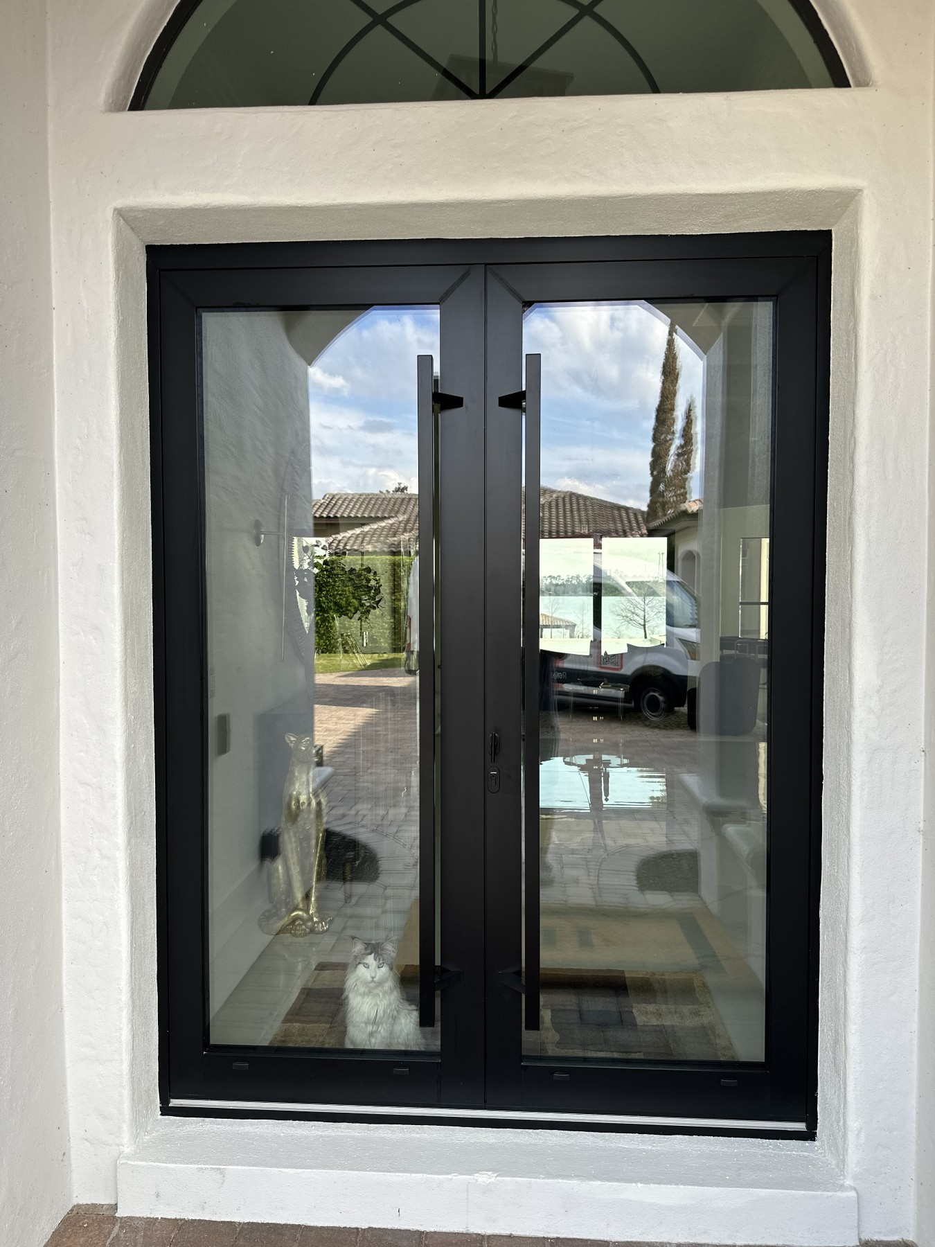 Black-framed glass French entry doors on a stucco Mediterranean-style home